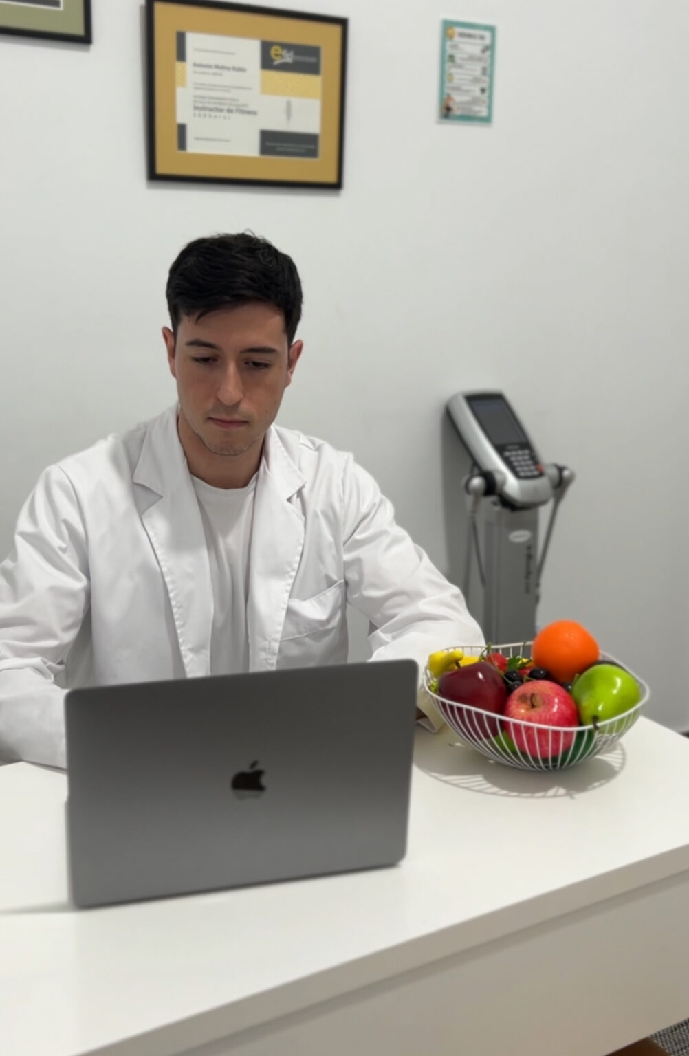 Consulta de nutrición de Novax: el dietista-nutricionista con un portátil y un frutero