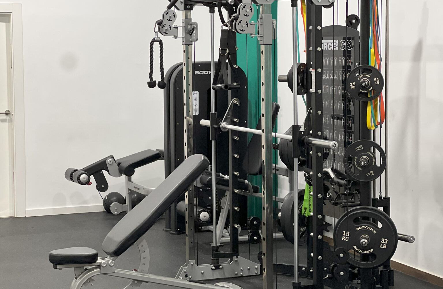 Máquina multiestación y banco en la sala de entrenamiento de Novax